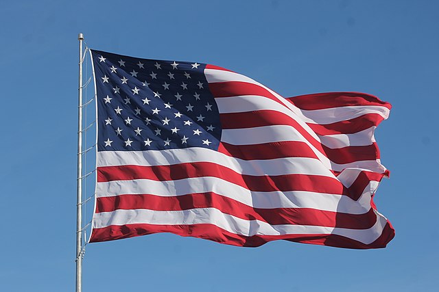 American_Flag_Waving_on_a_Flag_Pole-1 - Poli Alert American Flag