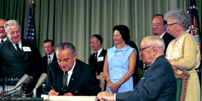 President Lyndon B. Johnson in 1965 signs the bill into law that established Medicare and Medicaid.