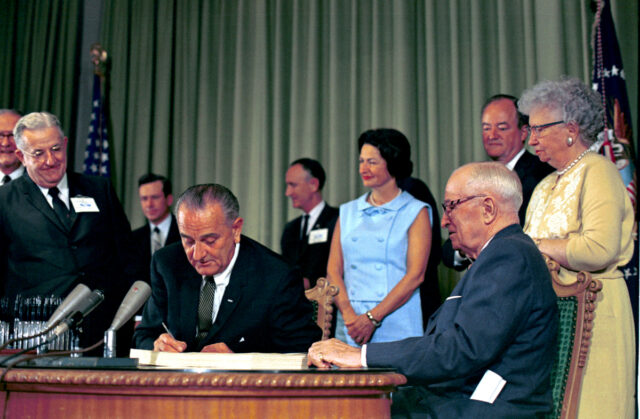 President Lyndon B. Johnson in 1965 signs the bill into law that established Medicare and Medicaid.