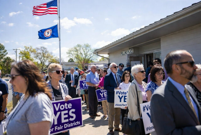 - Poli Alert Crowd of people holding 'Vote YES' signs outside a polling place, with American and state flags waving in the sky.