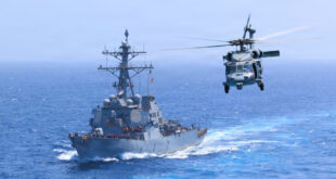 USS Donald Cook (DDG 75) transits the Arabian Sea while an MH-60S Sea Hawk flies nearby.