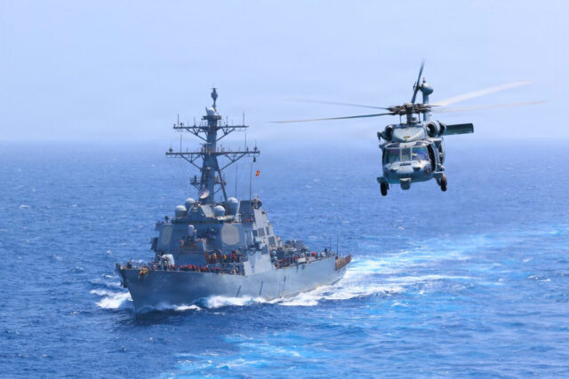Iran war - Poli Alert USS Donald Cook (DDG 75) transits the Arabian Sea while an MH-60S Sea Hawk flies nearby.