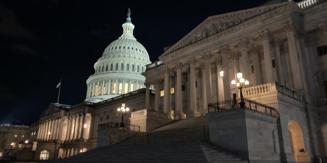 Night view of the U.S. Capitol with an illuminated dome and wide stone steps gradually rising toward the building.