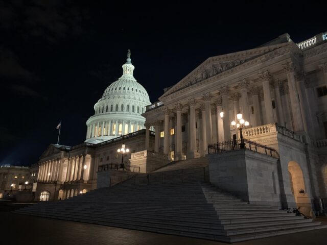 Night view of the U.S. Capitol with an illuminated dome and wide stone steps gradually rising toward the building.