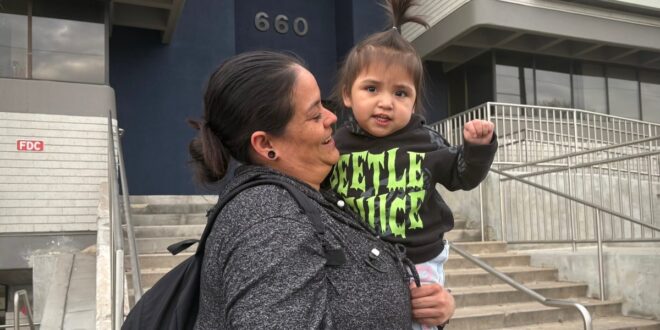 A mother and daughter are pictured at a protest against arrests of immigrants at green card appointments in Salt Lake City. Two lawsuits filed Monday challenge new federal guidance that could affect green card applicants who have used Medicaid or food assistance.